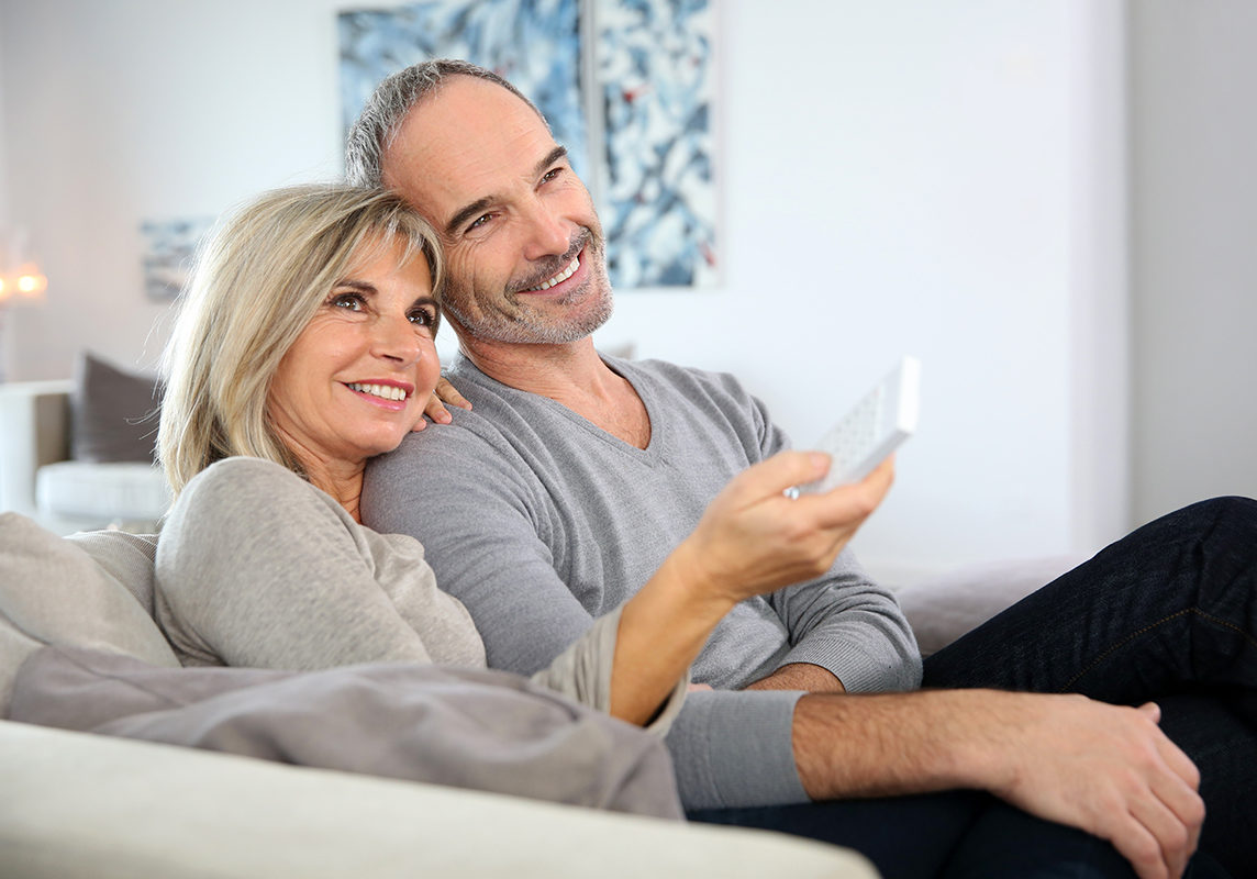 Senior couple sitting in couch and watching tv Senior couple sitting in couch and watching tv